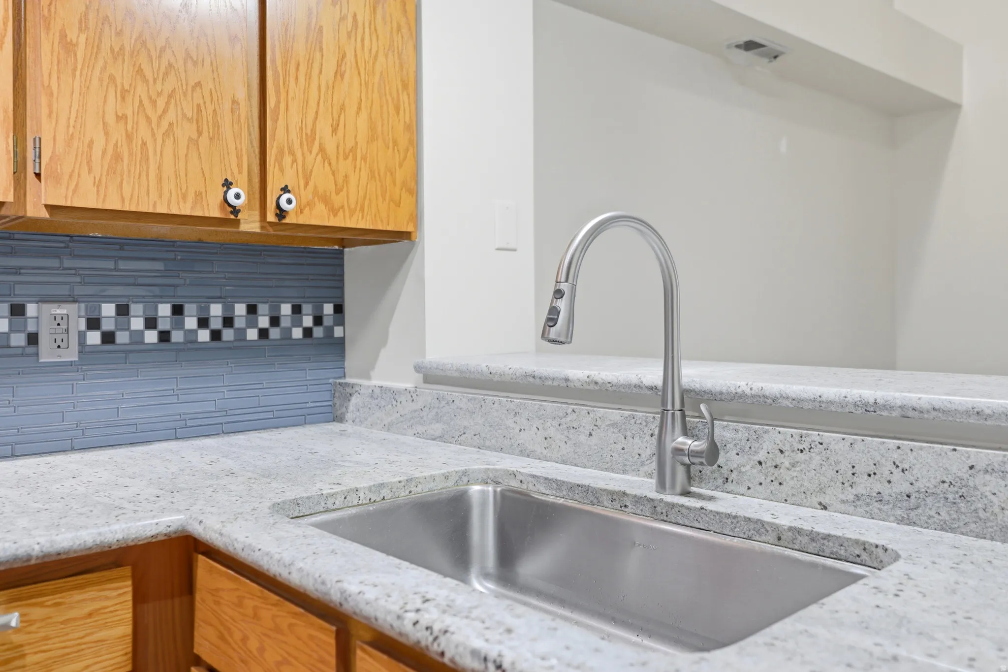 Stainless steel sink with a gooseneck faucet, set within a speckled countertop