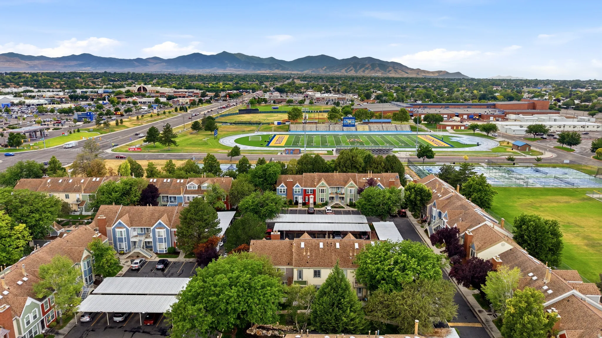 Aerial perspective showcasing tht community with covered parking, lush mature trees, and nearby athletic fields