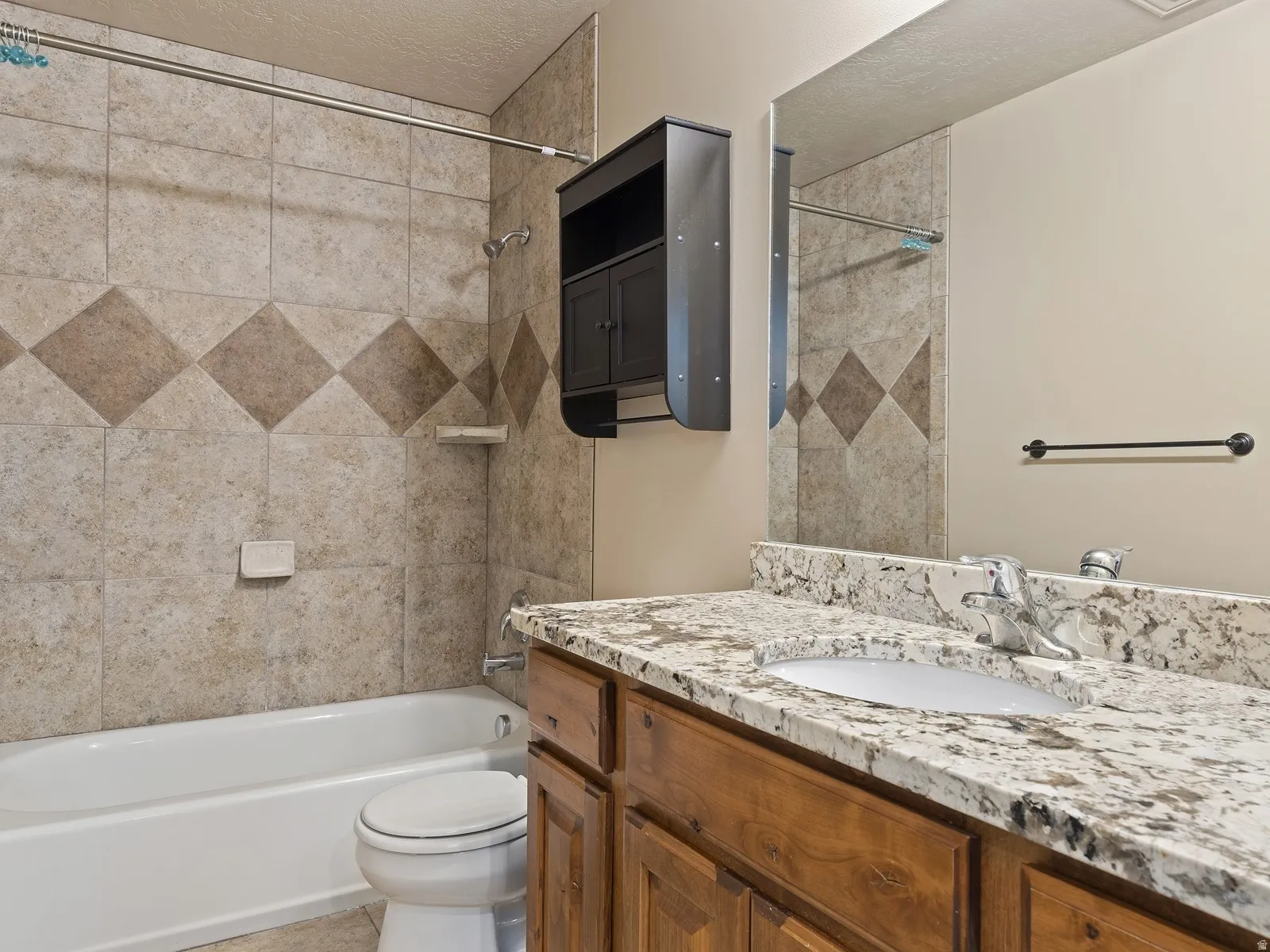 Bathroom featuring a wood-finish vanity with an integrated sink and a speckled countertop