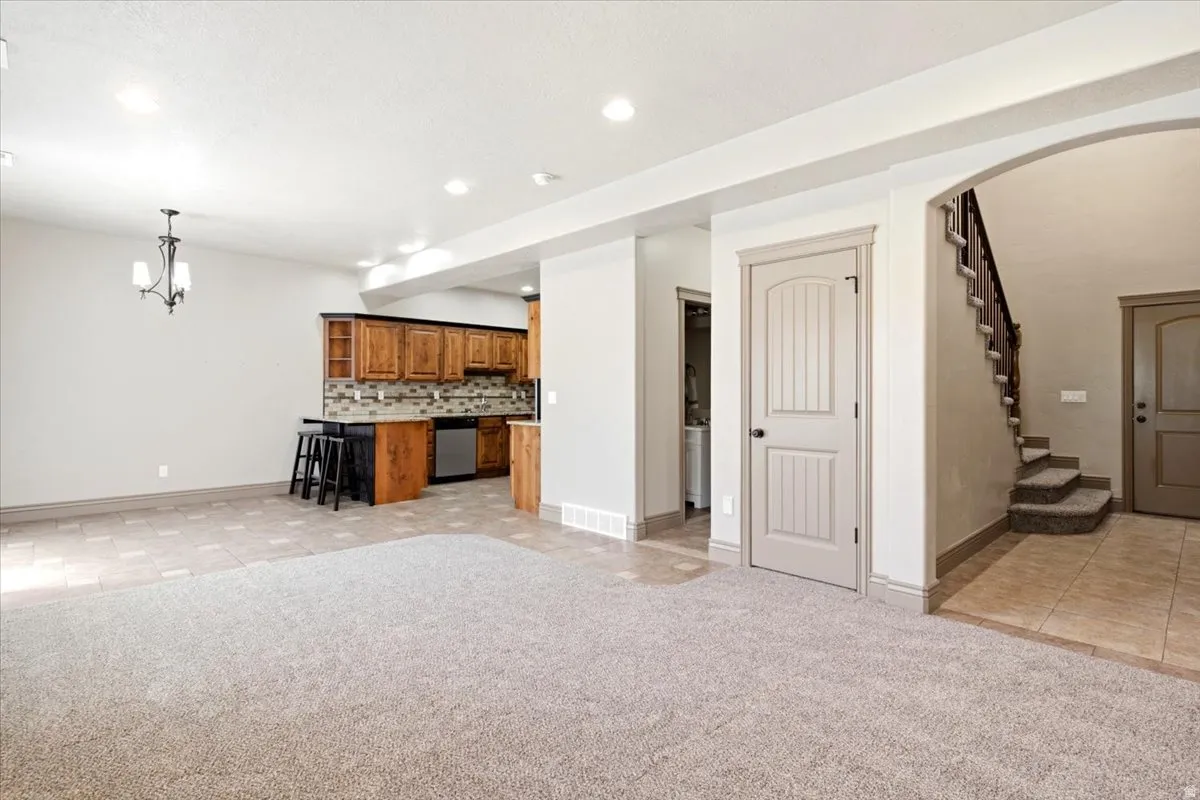 Spacious open-concept area featuring light-toned carpeting and tile flooring