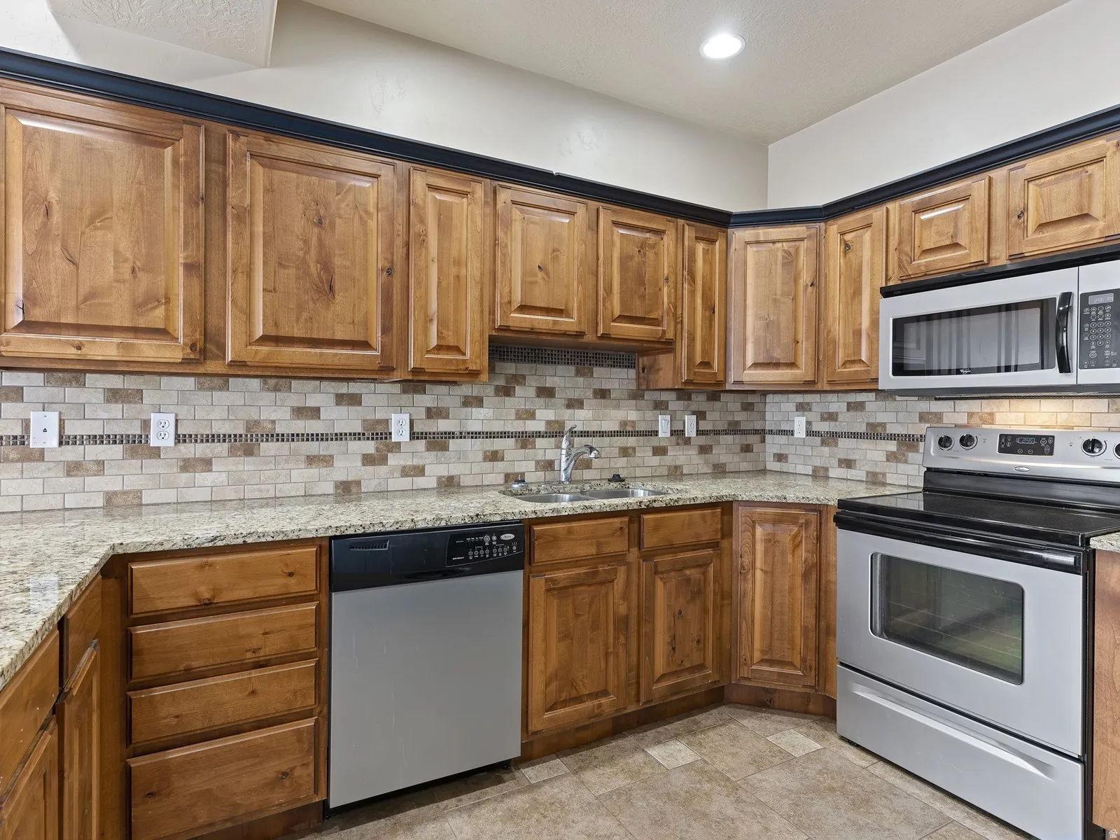 Kitchen featuring wood cabinetry, granite countertops, and a subway tile backsplash with accent strip