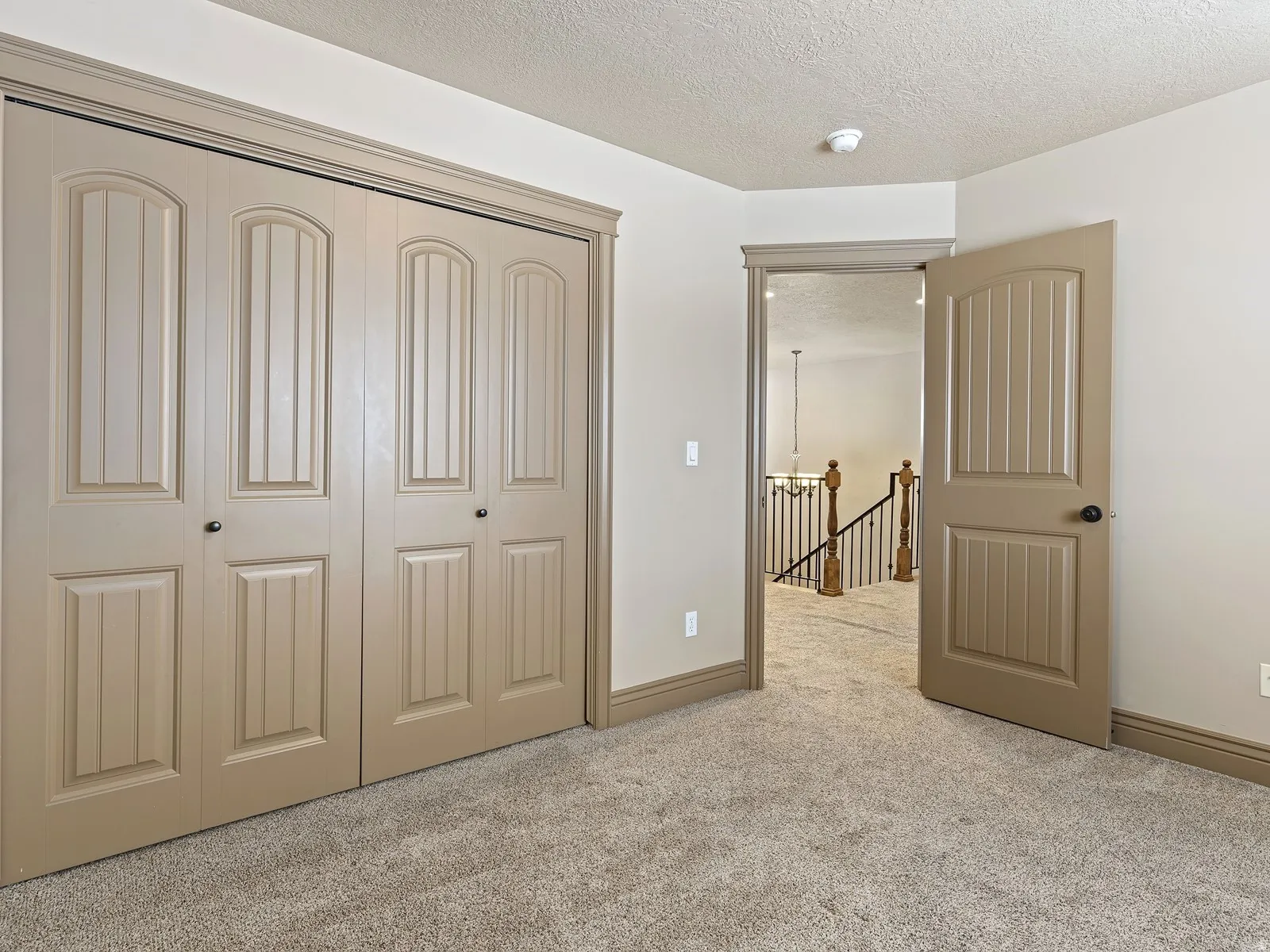 Neutral-toned paneled bifold closet doors with dark hardware, complemented by matching trim and baseboards
