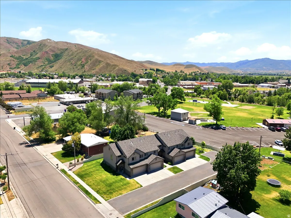 Aerial perspective showcasing a residential property with a multi-car garage, pitched shingle roof, and green lawn