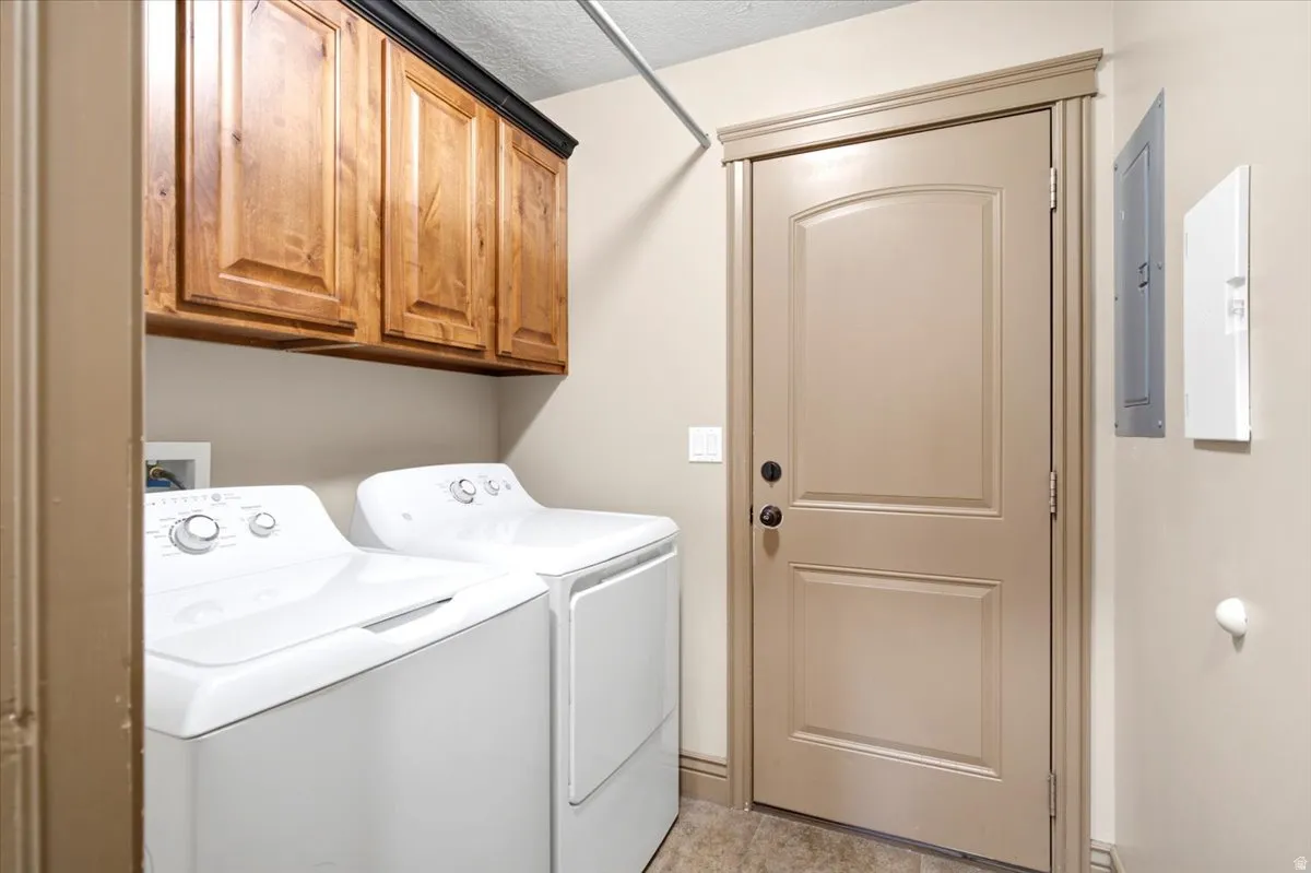 Laundry area featuring wood cabinetry, light beige walls, and tiled flooring