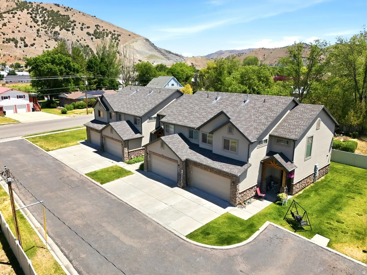 Twin townhome structures featuring stucco exteriors with stone accents, attached garages, and a pitched shingle roof