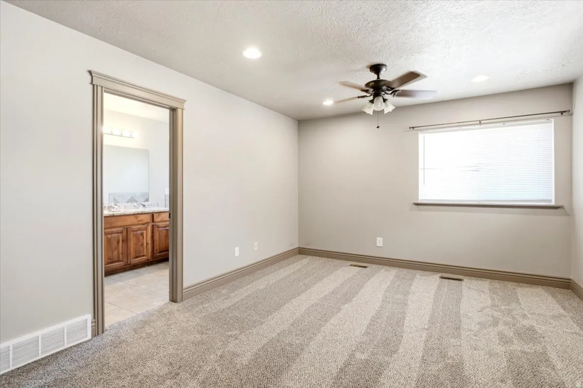 Neutral-toned bedroom featuring wall-to-wall carpeting, recessed lighting, and a ceiling fan
