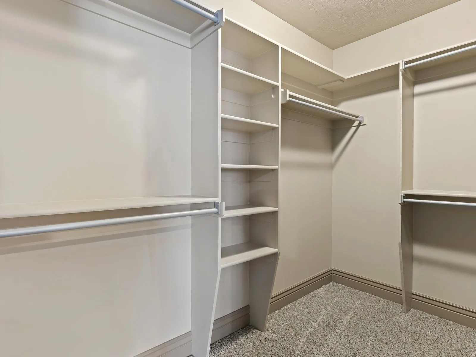 Integrated closet organization system featuring multiple hanging rods, shelving, and corner storage