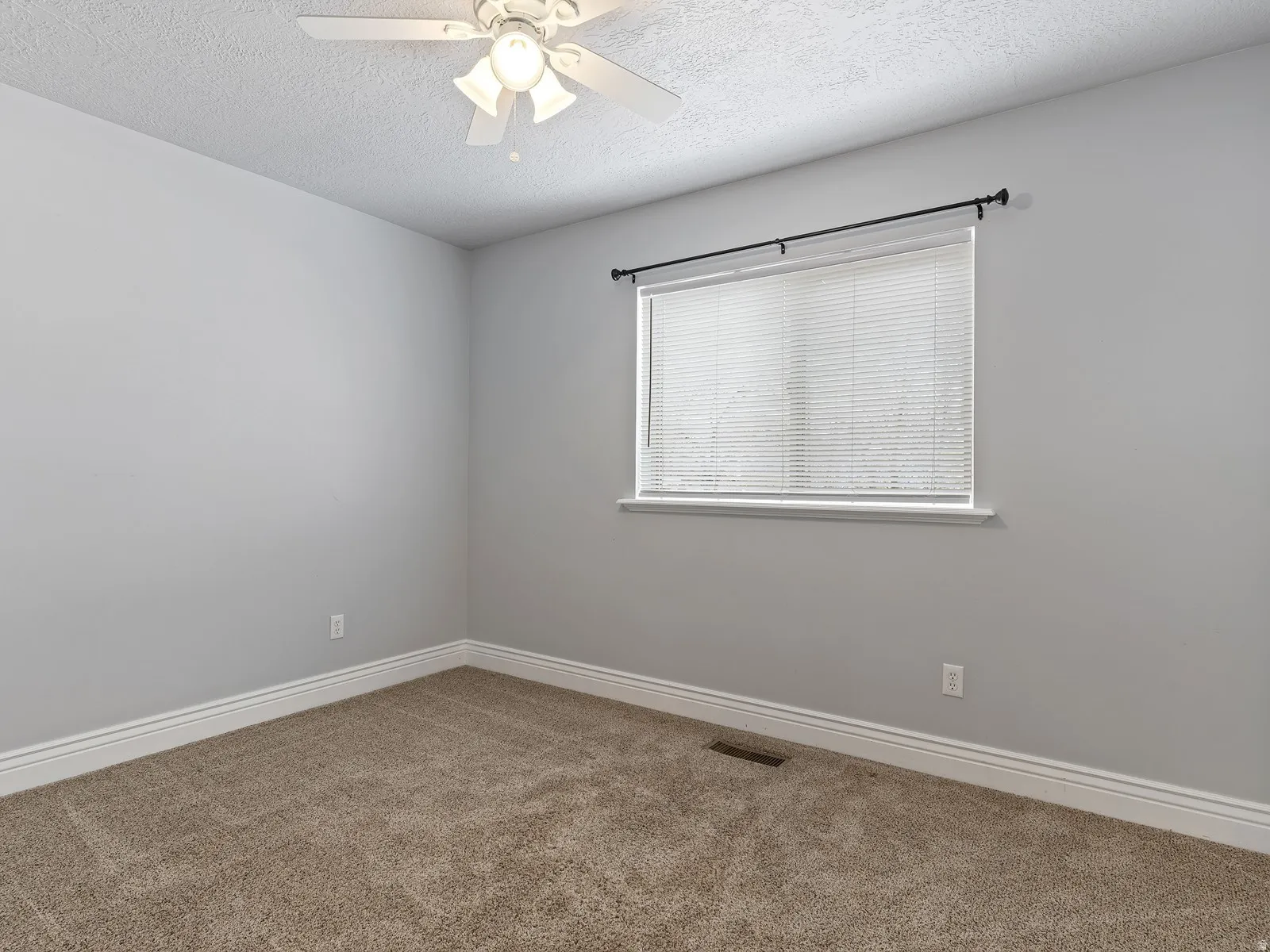 Carpeted room featuring a ceiling fan with integrated lighting, a window with blinds, and white baseboards