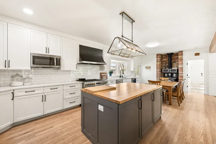 Kitchen featuring wood-finish flooring, white cabinetry with dark hardware, stainless steel appliances, and a subway tile backsplash