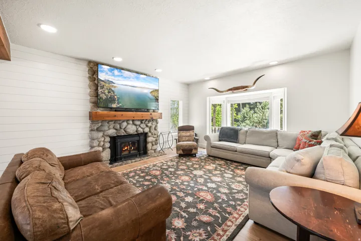 Spacious living area featuring a stone-faced fireplace with a wood mantle, shiplap accent wall, and recessed lighting