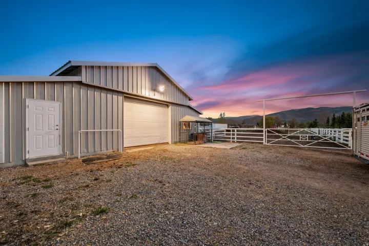 Metal-sided outbuilding featuring a white pedestrian door and large roll-up garage door