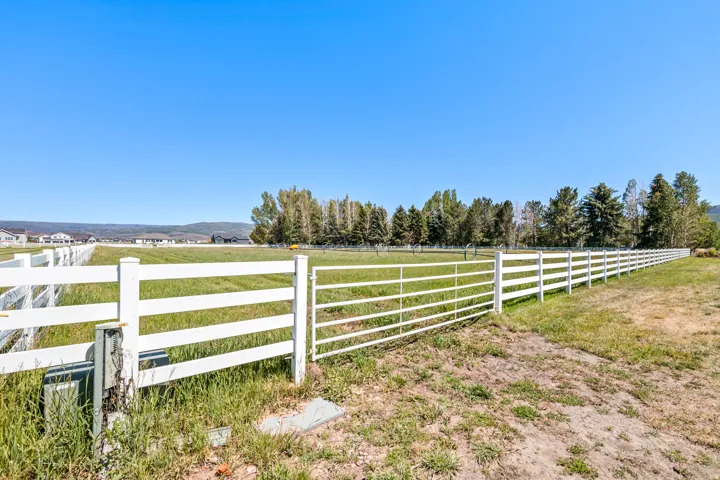 Expansive green pasture bordered by a white fence