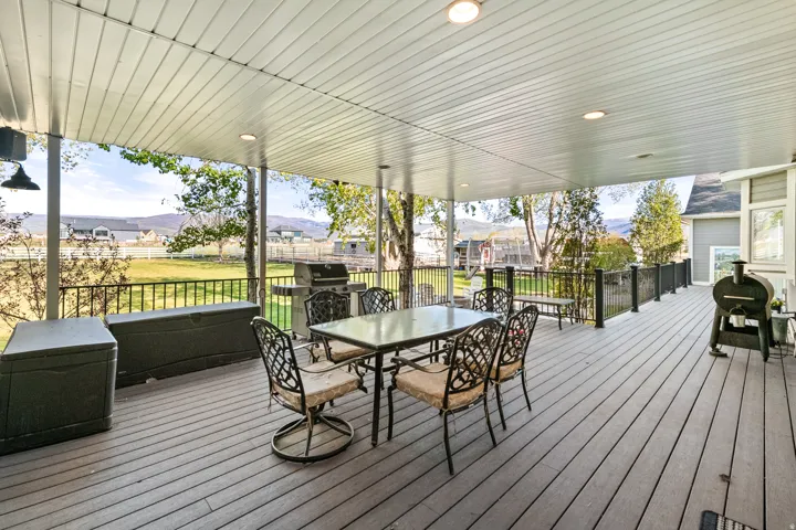 Spacious covered deck featuring a textured composite surface, recessed lighting, and a black metal railing