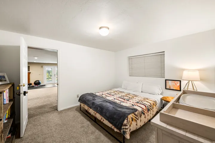 Carpeted room with a ceiling-mounted light fixture, white walls, and a window with horizontal blinds