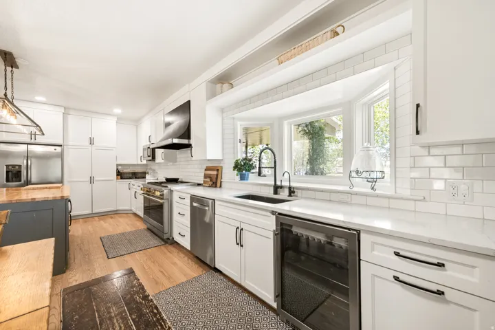 Contemporary kitchen featuring white cabinetry, subway tile backsplash, and light wood-finish flooring