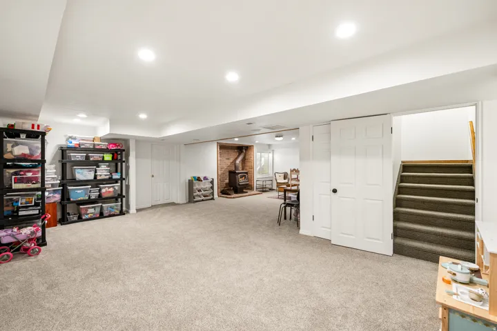 Finished lower level with recessed lighting, light carpeting, and a wood-burning stove with a brick surround