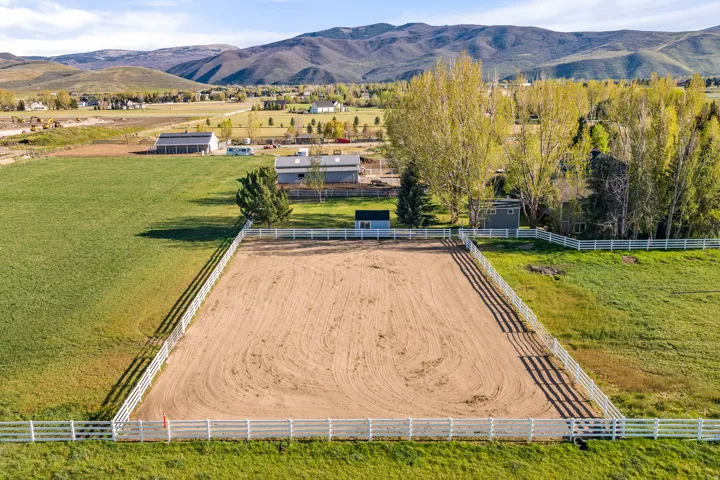 Expansive outdoor arena featuring a sand surface and white perimeter fencing