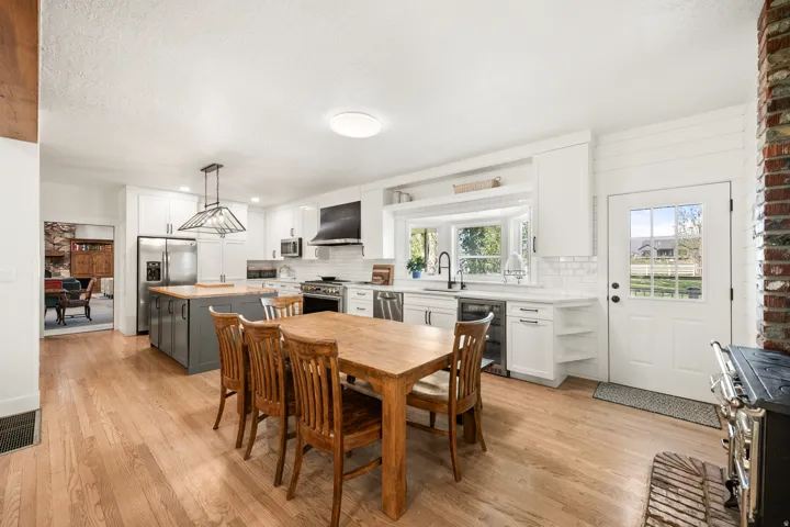 Bright kitchen featuring wood-finish flooring, white cabinetry, a central island with wood countertop, stainless steel appliances, and a bay window