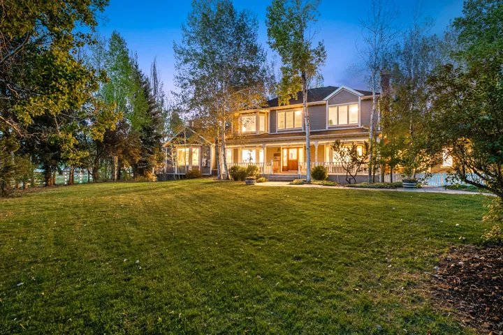 Two-story residence with a covered porch and multiple windows, set on a expansive lawn