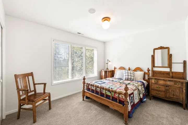 Spacious room featuring neutral carpeting, white walls, and a large window with blinds