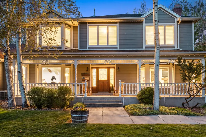 Traditional-style exterior featuring a covered porch with intricate spindle balustrades, a prominent bay window on the second story, and a wooden entry door with sidelights