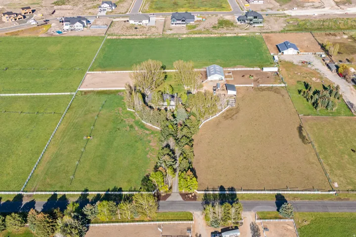 Expansive equestrian property featuring multiple fenced pastures, a large outbuilding, and mature perimeter trees providing natural screening