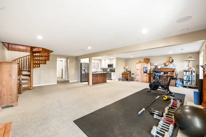 Expansive lower level featuring a spiral staircase with wood banister, recessed lighting, and light-toned carpet flooring