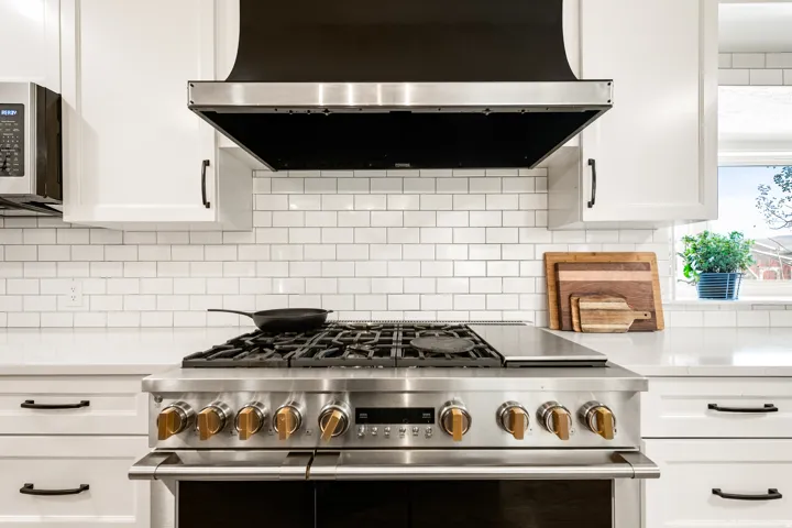 Stainless steel professional-grade range with a built-in griddle, complemented by a black and stainless steel range hood