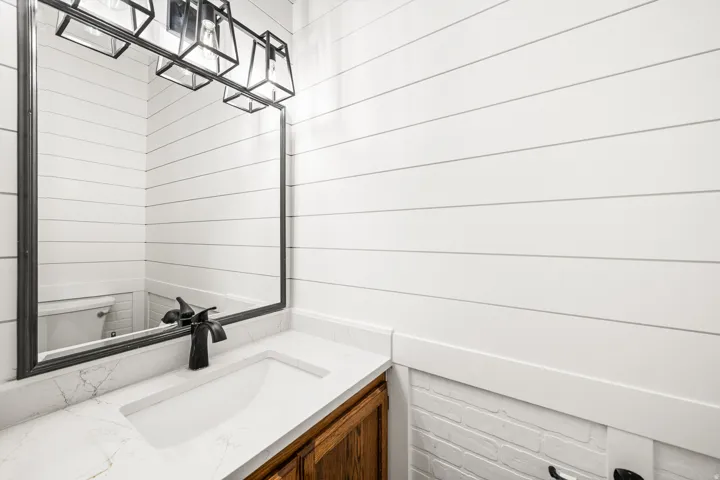 Bathroom vanity featuring a quartz countertop with an integrated sink, matte black faucet, and a large framed mirror