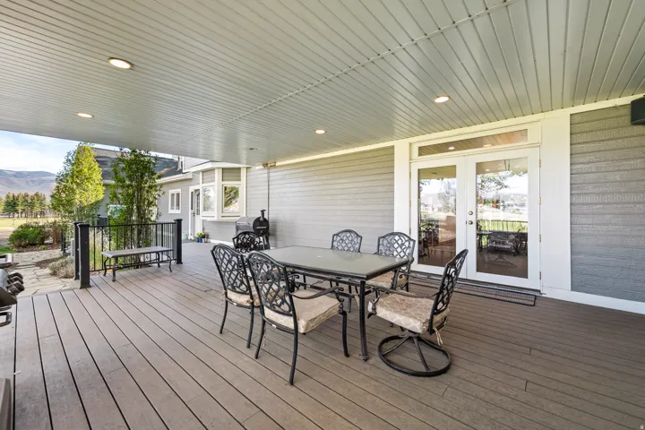 Expansive covered deck featuring composite decking, recessed lighting, and a mountain backdrop