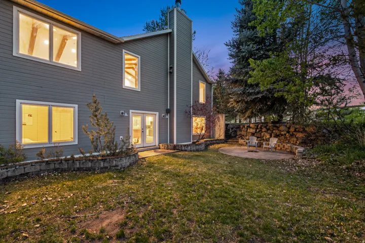 Rear exterior featuring gray horizontal siding, multiple windows, and a prominent chimney