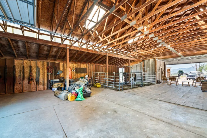 Spacious barn interior featuring exposed wood beam construction and a concrete floor