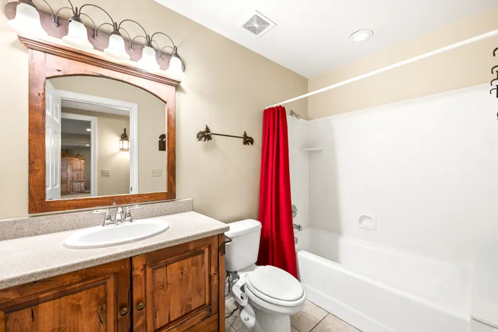 Full bathroom featuring a wood-finish vanity with a light-toned countertop, an undermount sink, and a framed mirror
