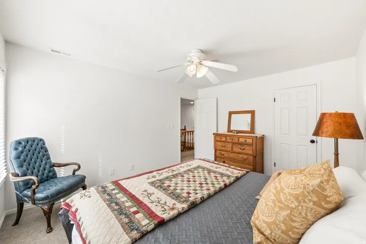Carpeted bedroom featuring a ceiling fan, white walls, and a window with blinds