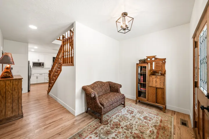 Entryway featuring wood-finish flooring, a wood staircase with balusters, and a decorative overhead light fixture