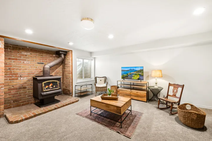 Exposed brick wall featuring a wood-burning stove with a brick hearth