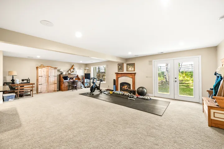 Spacious room featuring neutral carpet flooring, recessed lighting, and a built-in fireplace with a wood mantle and stone surround