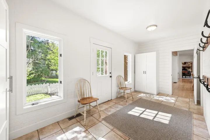 Bright entryway featuring tile flooring, white plank wall accents, and a built-in coat rack