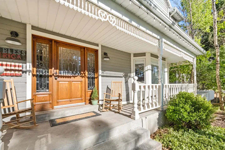 Inviting front porch featuring a prominent wood entry door with leaded glass sidelights, decorative white balustrades, and a bay window