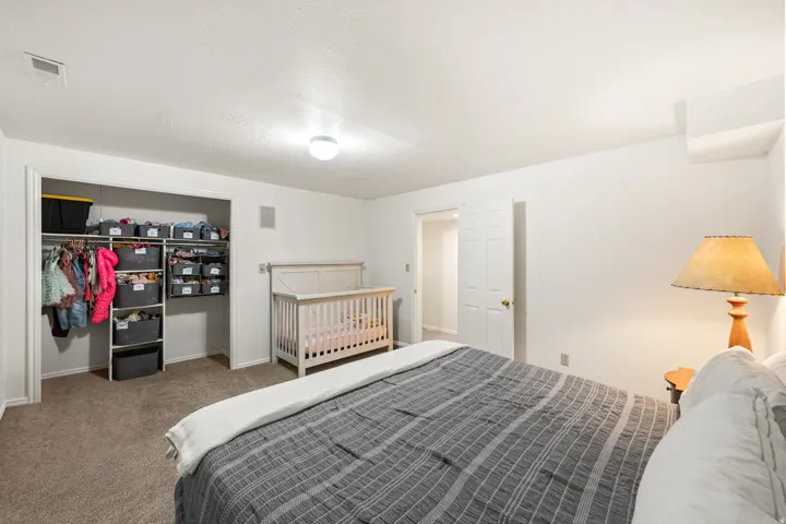 Bedroom featuring carpeting, white walls, and a built-in closet with organizational shelving