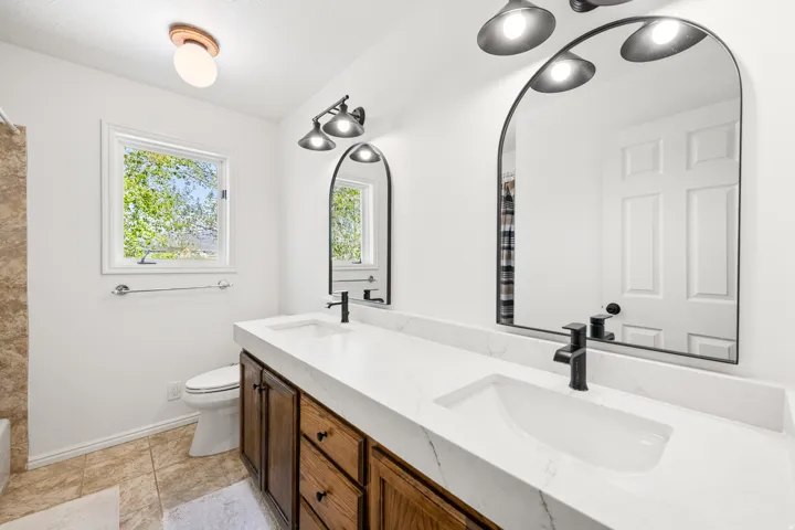 Double vanity featuring integrated sinks, a white quartz countertop, and rich wood cabinetry