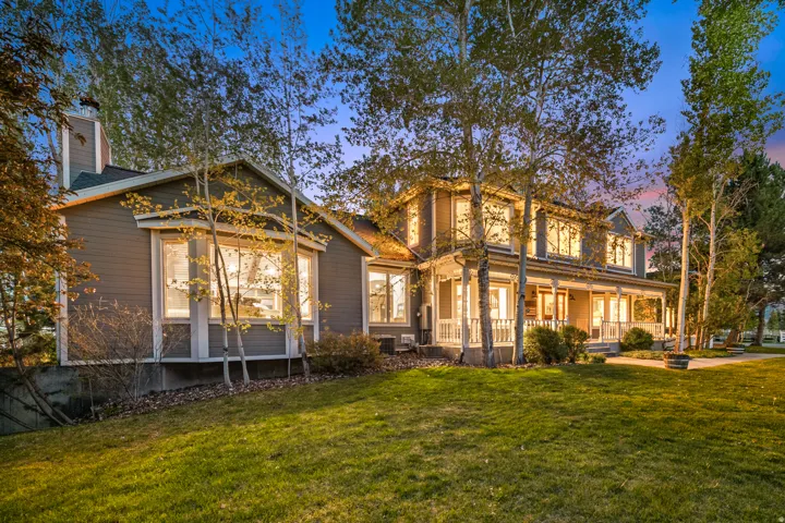 Two-story residence featuring a full-width covered front porch with white railings, multiple bay windows, and a prominent chimney