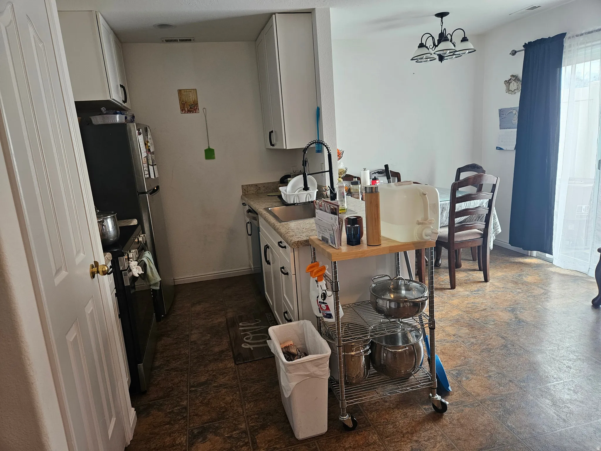 Compact kitchen area featuring white cabinetry, a stainless steel sink with a matte black faucet, and a black refrigerator