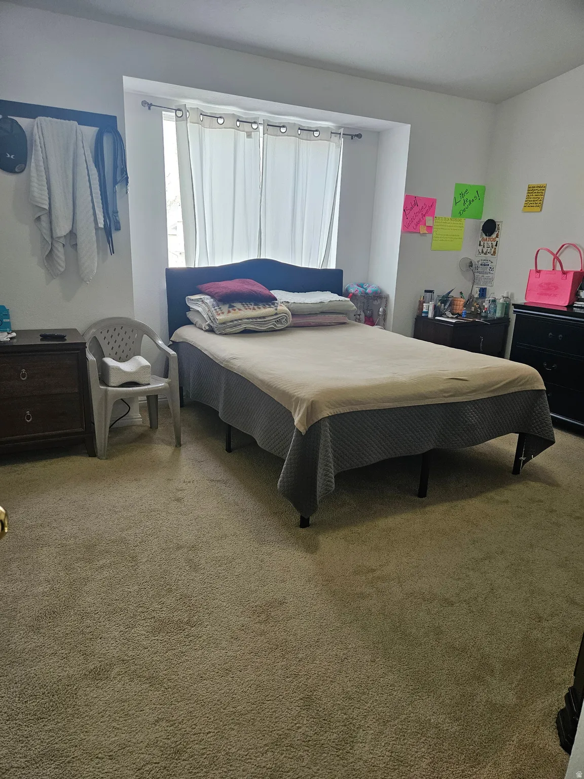 Spacious room featuring neutral carpeting and a large window with white curtains