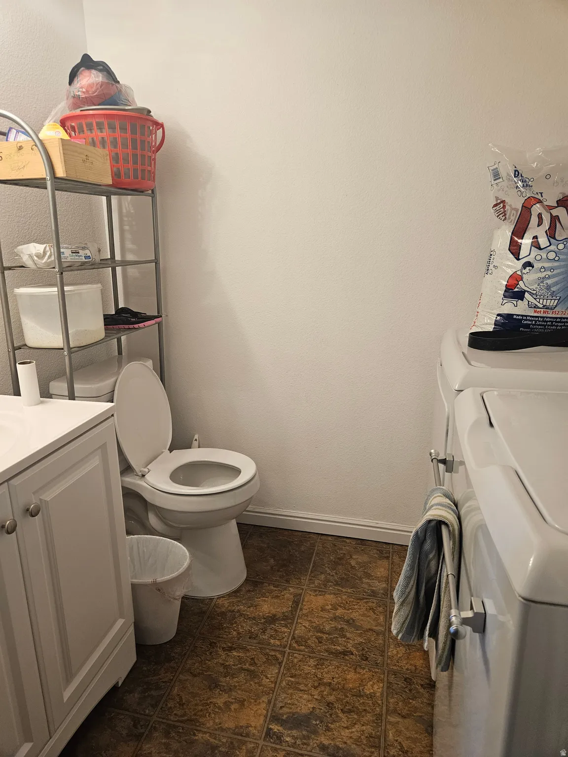 Laundry area featuring a built-in toilet, stone-look flooring, and white wall paint