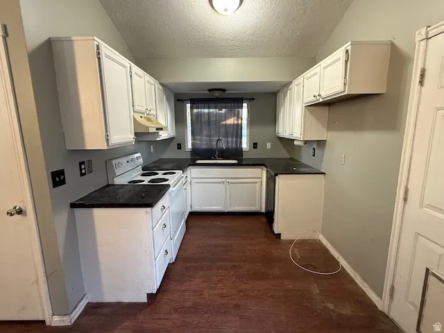U-shaped kitchen featuring white cabinetry, dark countertops, a white electric range, and a single basin sink with a window above