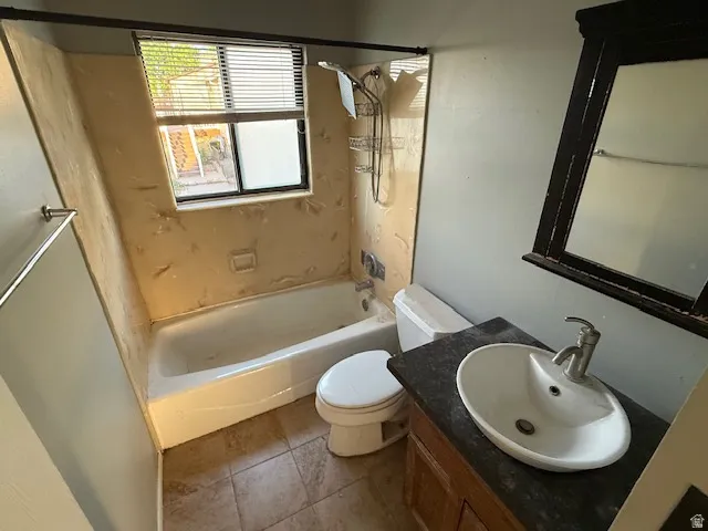 Bathroom featuring a built-in tub, tiled flooring, vanity with a vessel sink, and an integrated mirror