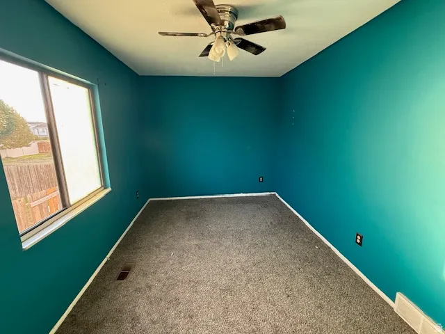 Room featuring teal walls, gray carpet, and a ceiling fan