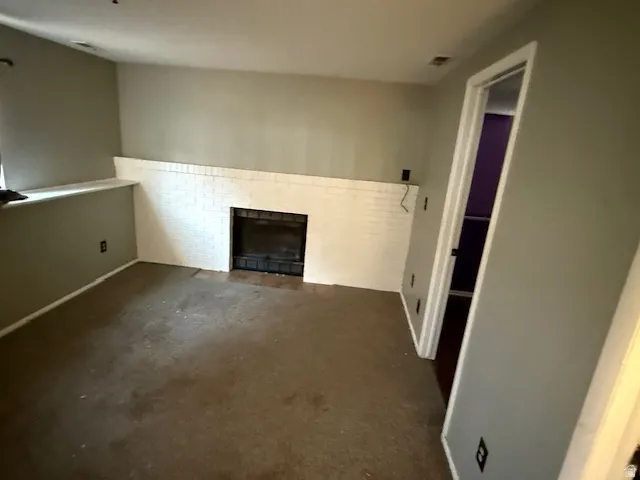Living space featuring a white brick fireplace with a dark firebox, a built-in ledge, and neutral-toned wall paint