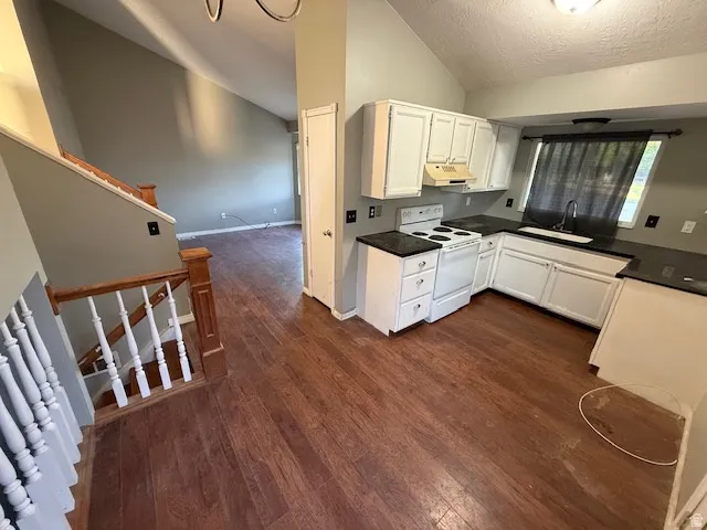 Kitchen featuring white cabinetry, dark countertops, and wood-finish flooring